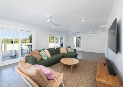 open lounge room with a long green couch in front of the tv in North Maleny Country Cottage