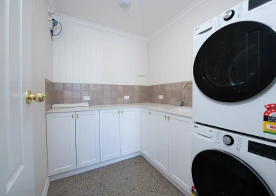 White laundry room with a dryer stacked on top of a washing machine in North Maleny Country Cottage