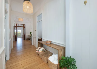 Long white country-style hallway with honey-coloured floorboards in North Maleny Country Cottage