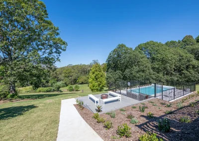 view of a fire pit with three benches and a fenced off pool outside North Maleny Country Cottage